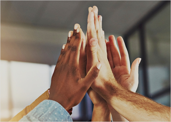Group of 5 hands giving a high five in the air.