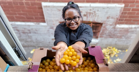 In this image, a woman's hand is holding a yellow berries.
